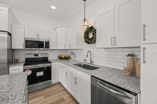 kitchen featuring backsplash, sink, light hardwood / wood-style floors, white cabinetry, and stainless steel appliances