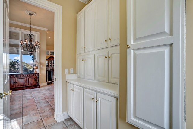 interior space with a chandelier, crown molding, baseboards, and light tile patterned floors