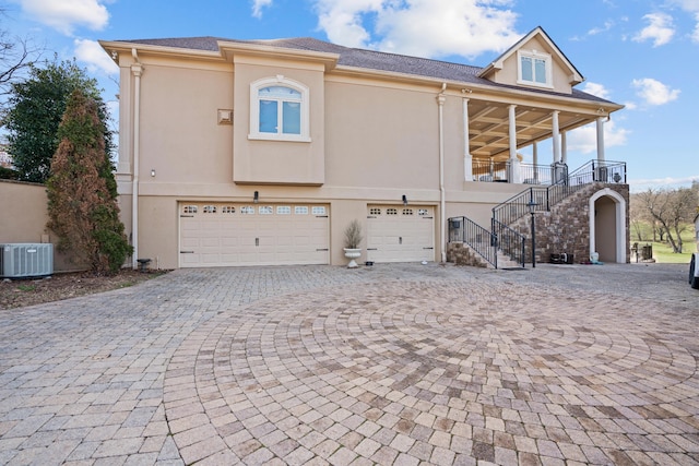 view of front of home with stairs, decorative driveway, a garage, and stucco siding