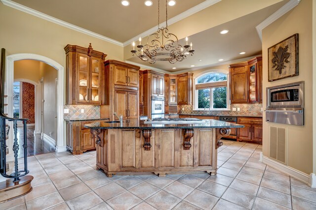 kitchen featuring arched walkways, a kitchen breakfast bar, brown cabinets, built in appliances, and a warming drawer