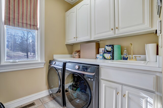 clothes washing area with light tile patterned floors, cabinet space, a sink, separate washer and dryer, and baseboards