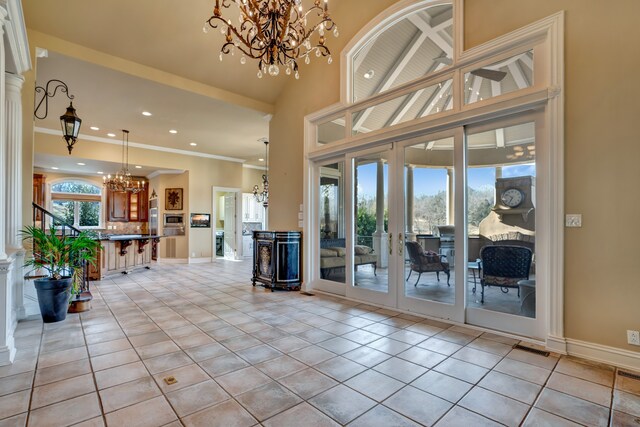 entryway featuring light tile patterned floors, baseboards, an inviting chandelier, crown molding, and french doors