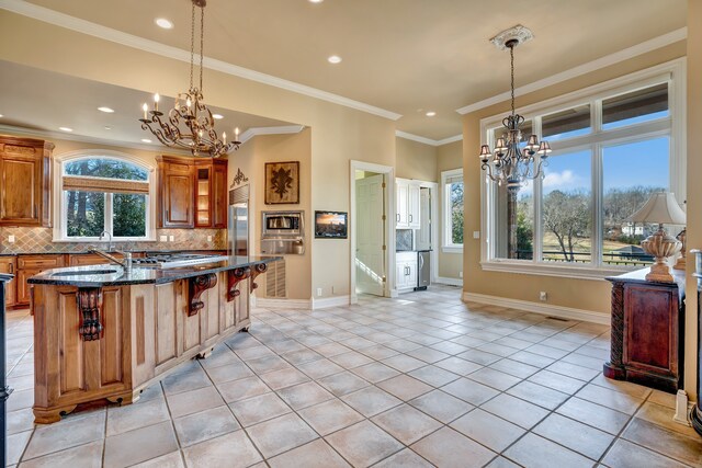 kitchen with brown cabinets, a notable chandelier, backsplash, and a breakfast bar area