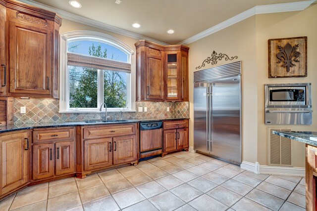 kitchen featuring built in appliances, a sink, a warming drawer, brown cabinetry, and crown molding