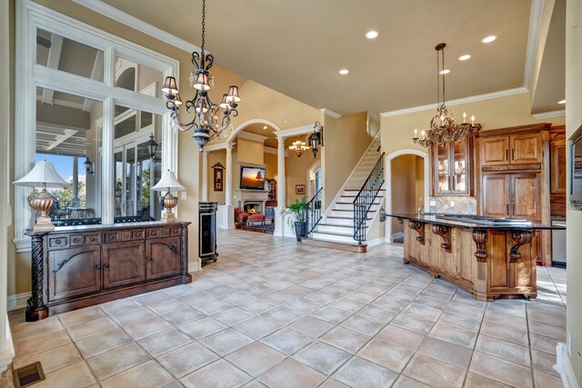 kitchen featuring a warm lit fireplace, arched walkways, and a notable chandelier