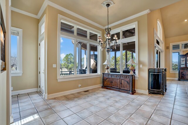 unfurnished dining area featuring baseboards, crown molding, an inviting chandelier, and light tile patterned floors