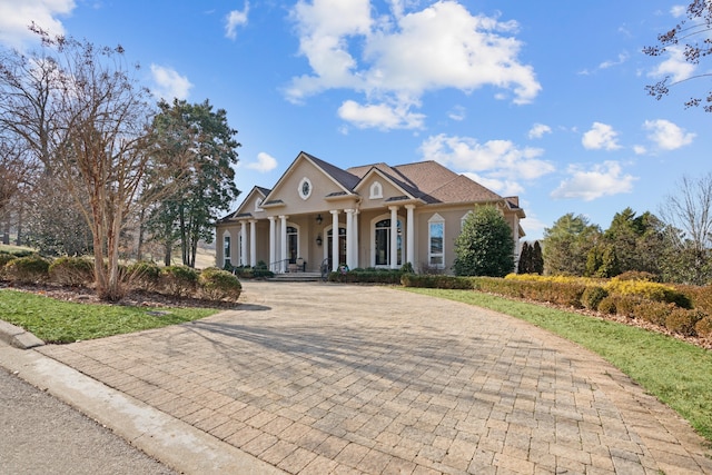 greek revival house with decorative driveway and stucco siding