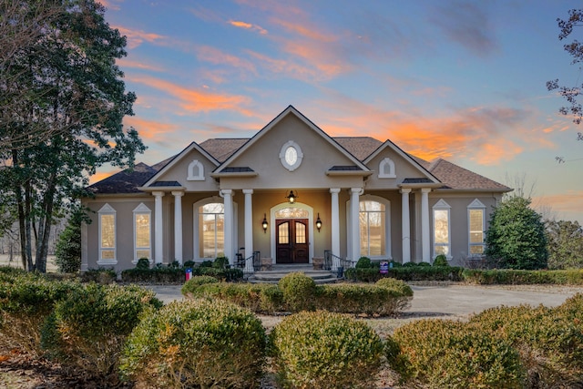 neoclassical home with covered porch, driveway, french doors, and stucco siding