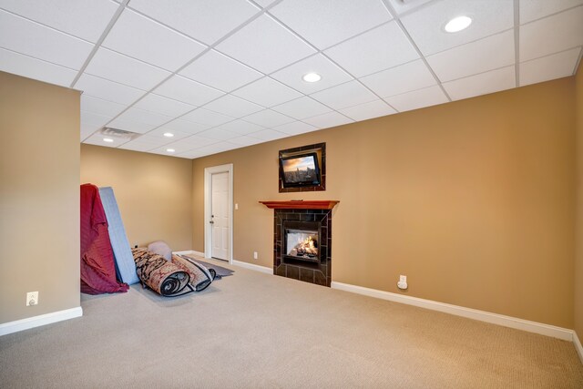 unfurnished room featuring a drop ceiling, a tile fireplace, recessed lighting, carpet flooring, and baseboards