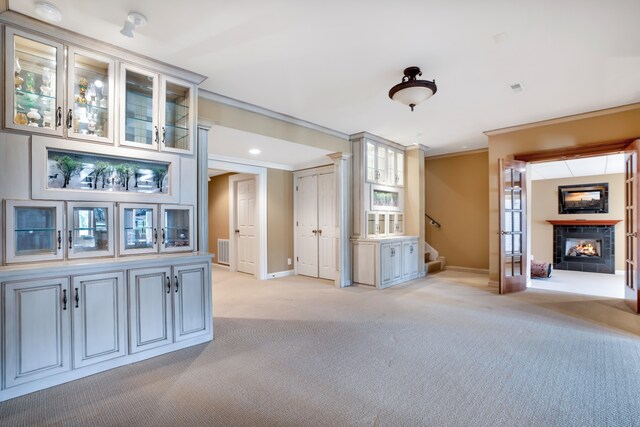 unfurnished living room with light colored carpet, a fireplace, visible vents, stairs, and crown molding