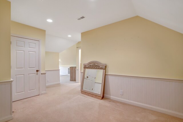 unfurnished room featuring recessed lighting, carpet flooring, visible vents, vaulted ceiling, and wainscoting