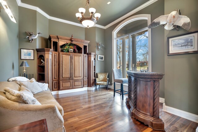 sitting room featuring a notable chandelier, baseboards, crown molding, and wood finished floors