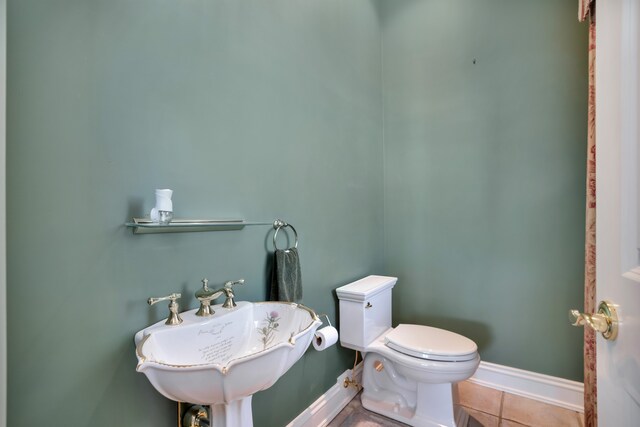 bathroom with toilet, tile patterned flooring, baseboards, and a sink