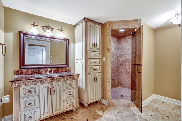 bathroom with a shower stall, baseboards, and vanity