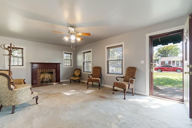 sitting room with ceiling fan, light carpet, and a brick fireplace