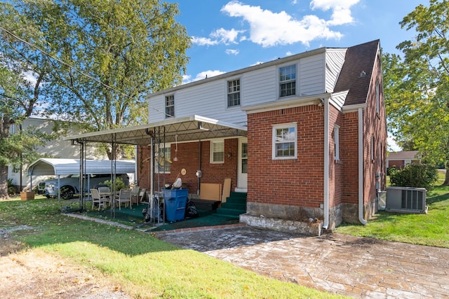 back of property featuring a carport, a lawn, and central AC unit