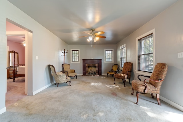 sitting room featuring ceiling fan, light colored carpet, and a brick fireplace