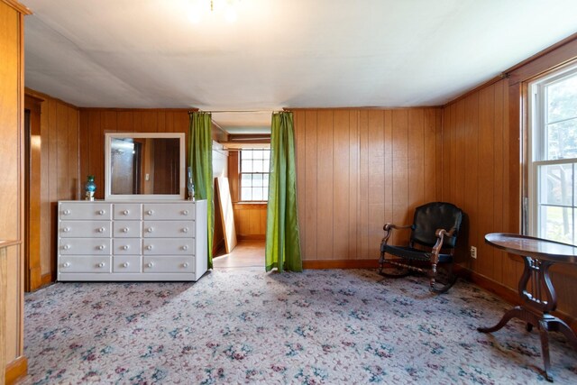 unfurnished bedroom featuring wood walls, light colored carpet, and multiple windows