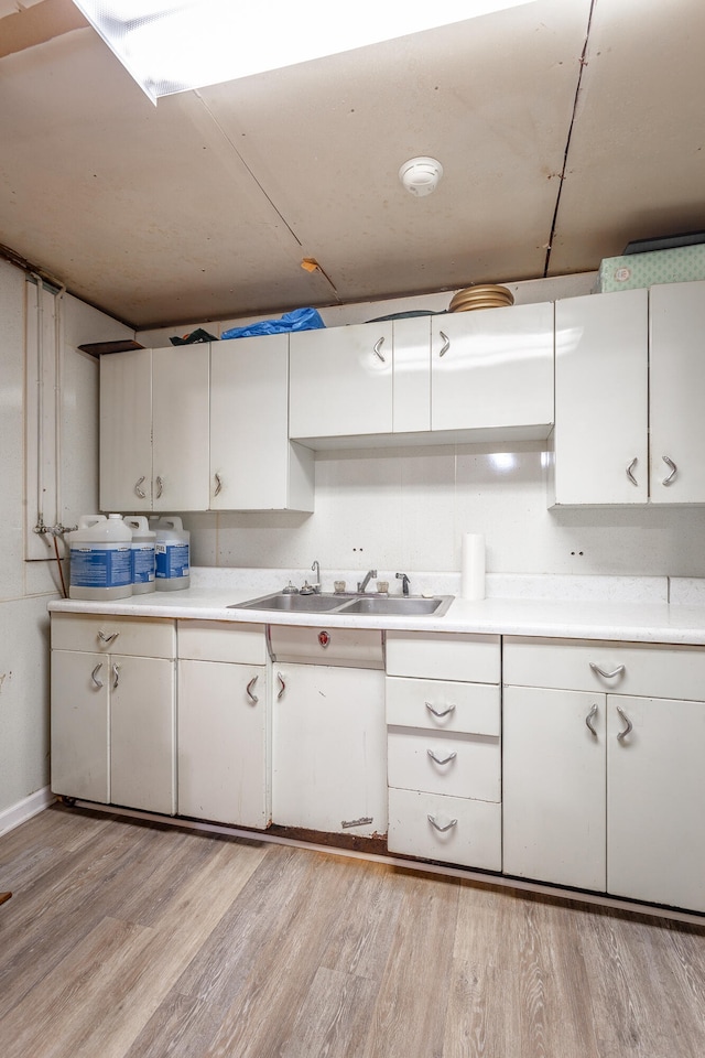 kitchen with light hardwood / wood-style flooring, sink, and white cabinetry