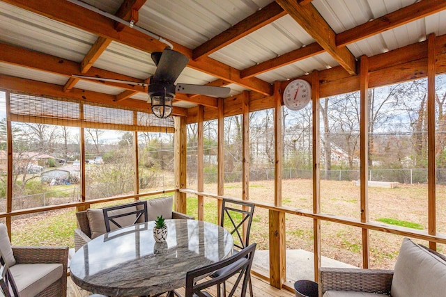 sunroom with ceiling fan and beam ceiling