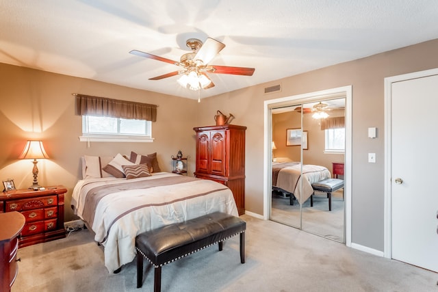 carpeted bedroom featuring ceiling fan, multiple windows, and a closet