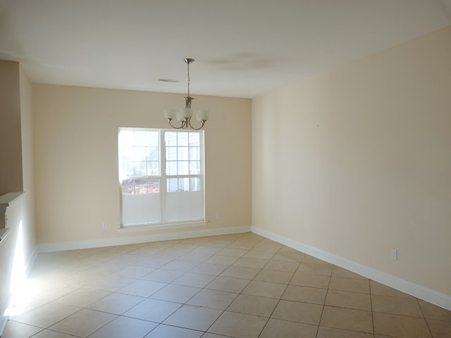 tiled empty room with a chandelier