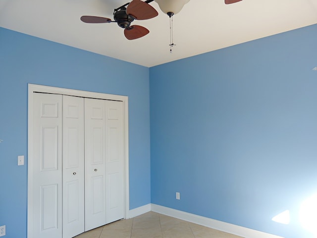 unfurnished bedroom featuring ceiling fan, light tile flooring, and a closet