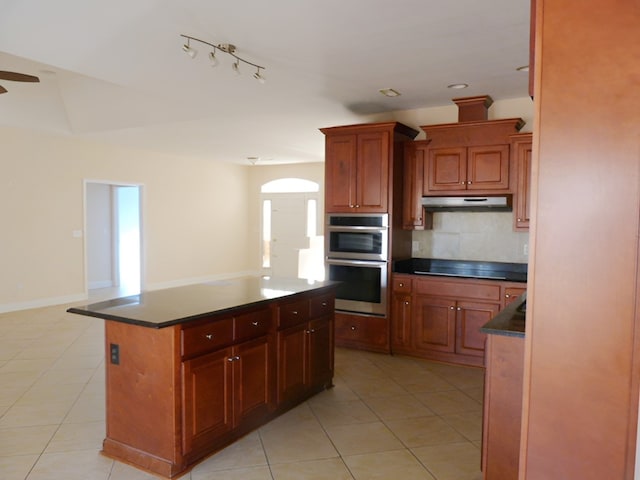 kitchen featuring a kitchen island, backsplash, light tile floors, double oven, and rail lighting