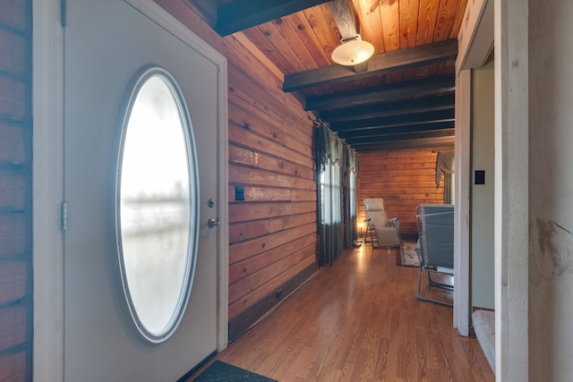 foyer featuring wooden walls, beam ceiling, dark wood-type flooring, and a wealth of natural light