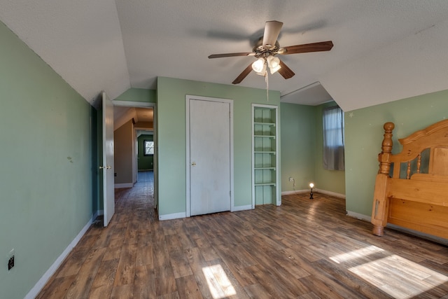 unfurnished bedroom with ceiling fan, lofted ceiling, dark wood-type flooring, and a textured ceiling