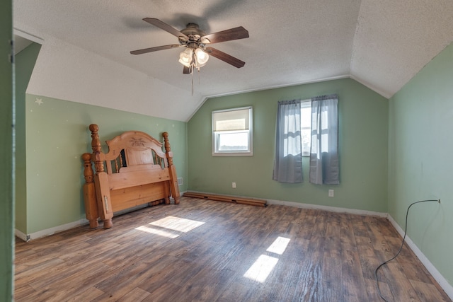 unfurnished bedroom with dark hardwood / wood-style flooring, ceiling fan, a textured ceiling, and vaulted ceiling