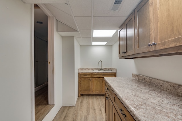 kitchen featuring light wood-type flooring, sink, and a paneled ceiling