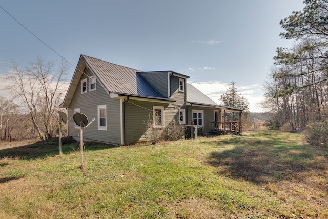 rear view of property featuring central AC unit and a lawn