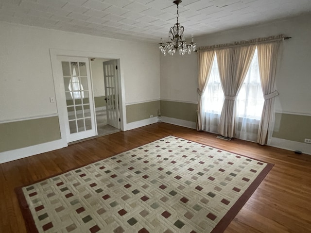 unfurnished room featuring a chandelier and light wood-type flooring