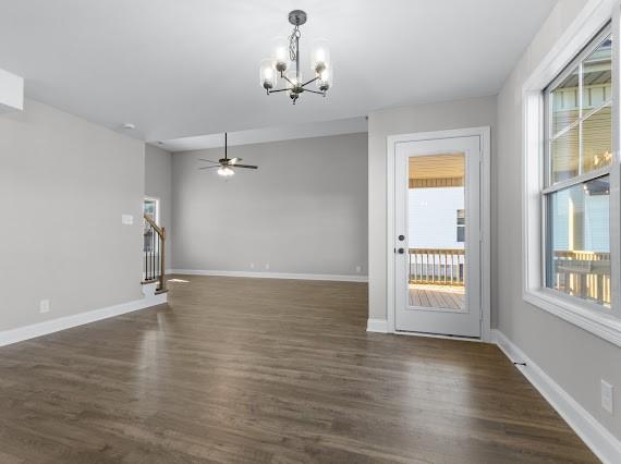 interior space with ceiling fan with notable chandelier, plenty of natural light, and dark hardwood / wood-style flooring