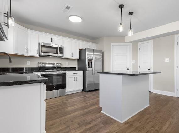 kitchen featuring appliances with stainless steel finishes, pendant lighting, white cabinetry, and a kitchen island