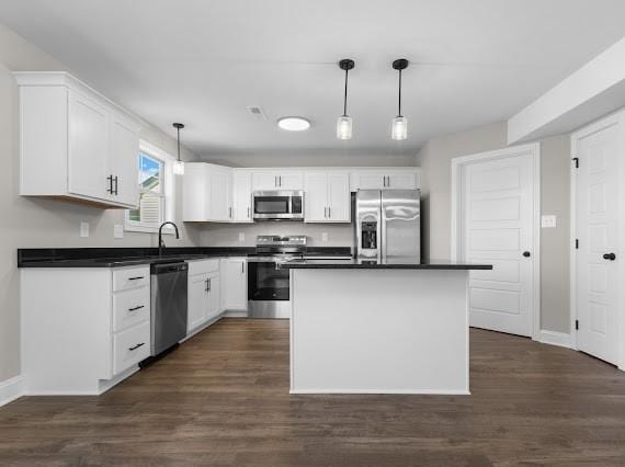 kitchen with pendant lighting, white cabinetry, appliances with stainless steel finishes, and a kitchen island