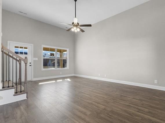 unfurnished living room with a high ceiling, ceiling fan, and dark hardwood / wood-style floors