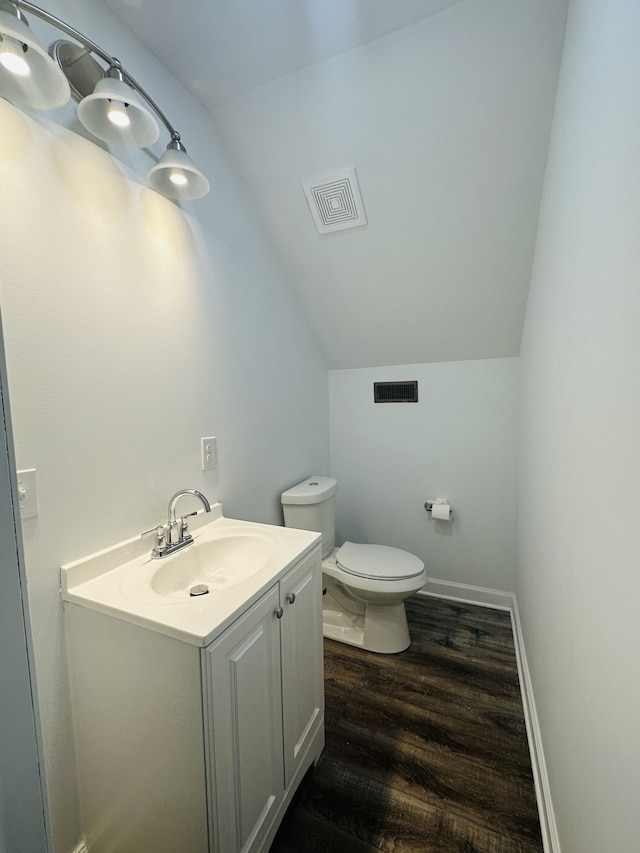 bathroom with toilet, vanity, hardwood / wood-style flooring, and vaulted ceiling