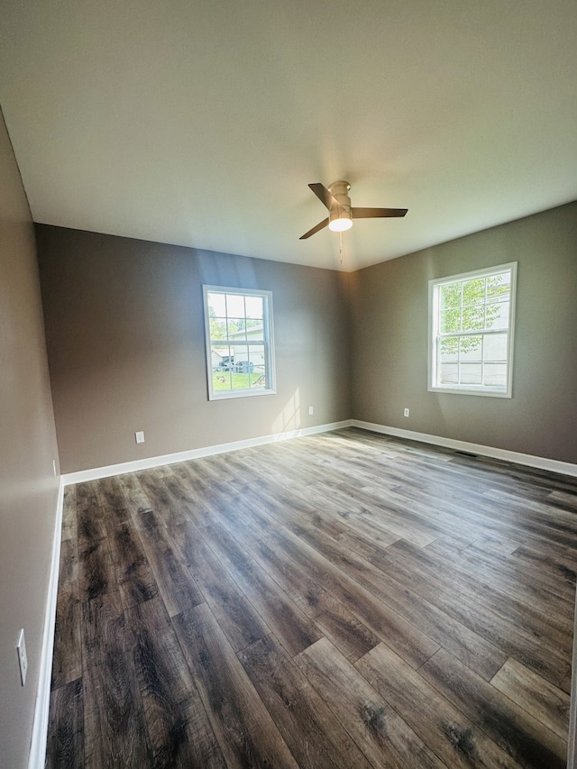 empty room featuring dark hardwood / wood-style floors, a healthy amount of sunlight, and ceiling fan