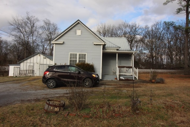 view of property exterior with covered porch, an outdoor structure, and a garage