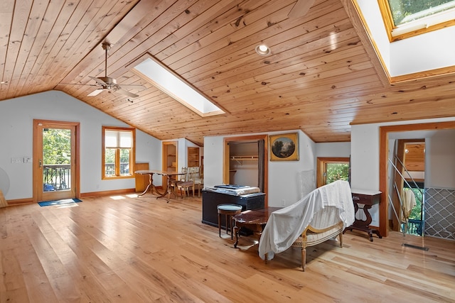 interior space with lofted ceiling with skylight, ceiling fan, and light wood-type flooring