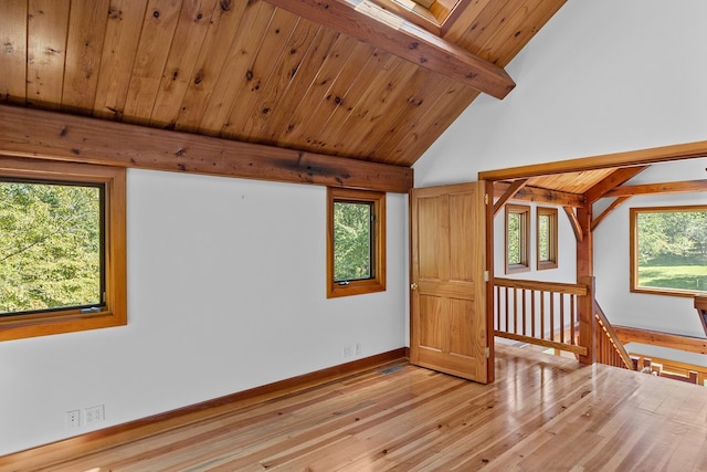 spare room featuring lofted ceiling with skylight, light hardwood / wood-style floors, and a wealth of natural light