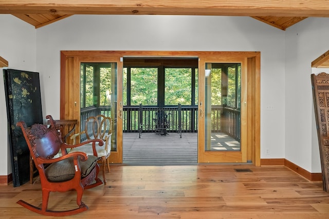 doorway with lofted ceiling with beams, wood ceiling, light hardwood / wood-style floors, and plenty of natural light