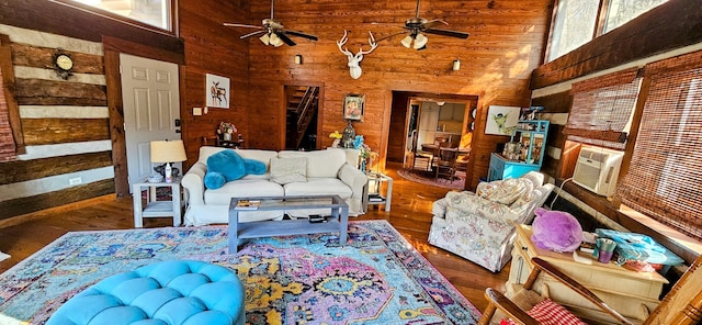 living room with wooden walls, a towering ceiling, ceiling fan, and dark hardwood / wood-style flooring