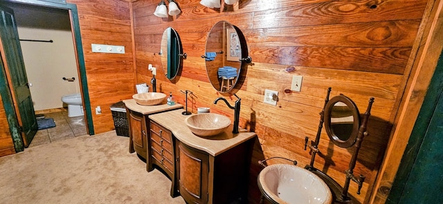 bathroom with vanity, wood walls, tile flooring, and toilet