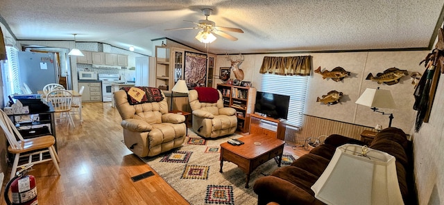 living room with plenty of natural light, vaulted ceiling, ceiling fan, and light wood-type flooring