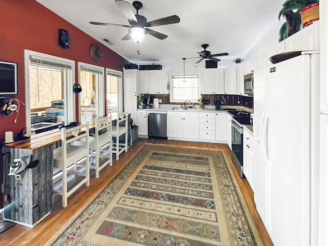 kitchen featuring stainless steel appliances, ceiling fan, dark wood-type flooring, lofted ceiling, and sink