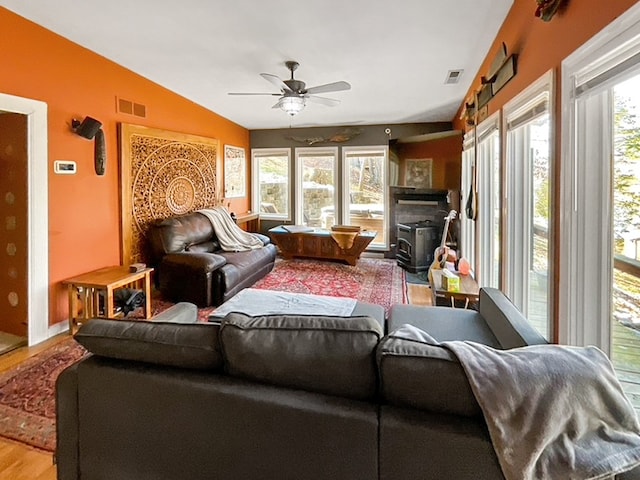 living room with a wood stove, ceiling fan, lofted ceiling, and light hardwood / wood-style flooring