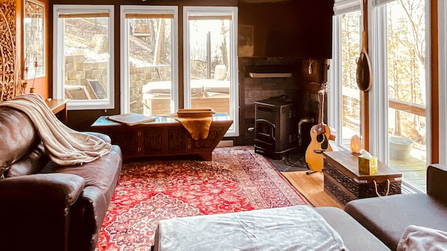 living area with a wood stove, a healthy amount of sunlight, and hardwood / wood-style flooring